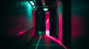 Narrow backstage corridor with clock and hot pink stage light bleeding through far door