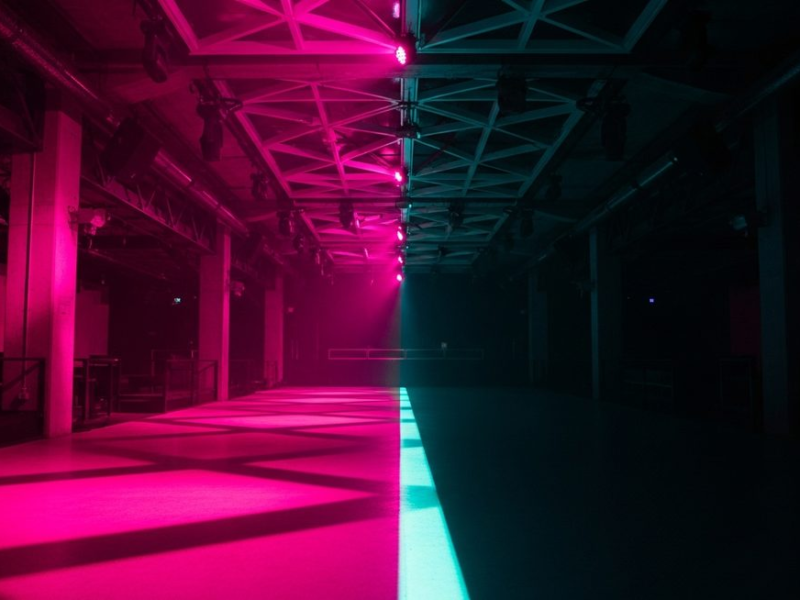 Nightclub interior dramatically split by light, one half bathed in hot pink neon, other half in total shadow, teal floor accent