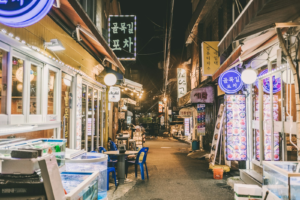 A narrow Itaewon-dong alley at night, lit tent bars and stacked crates, Seoul
