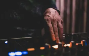 A DJ's hand on the mixer in a dark booth