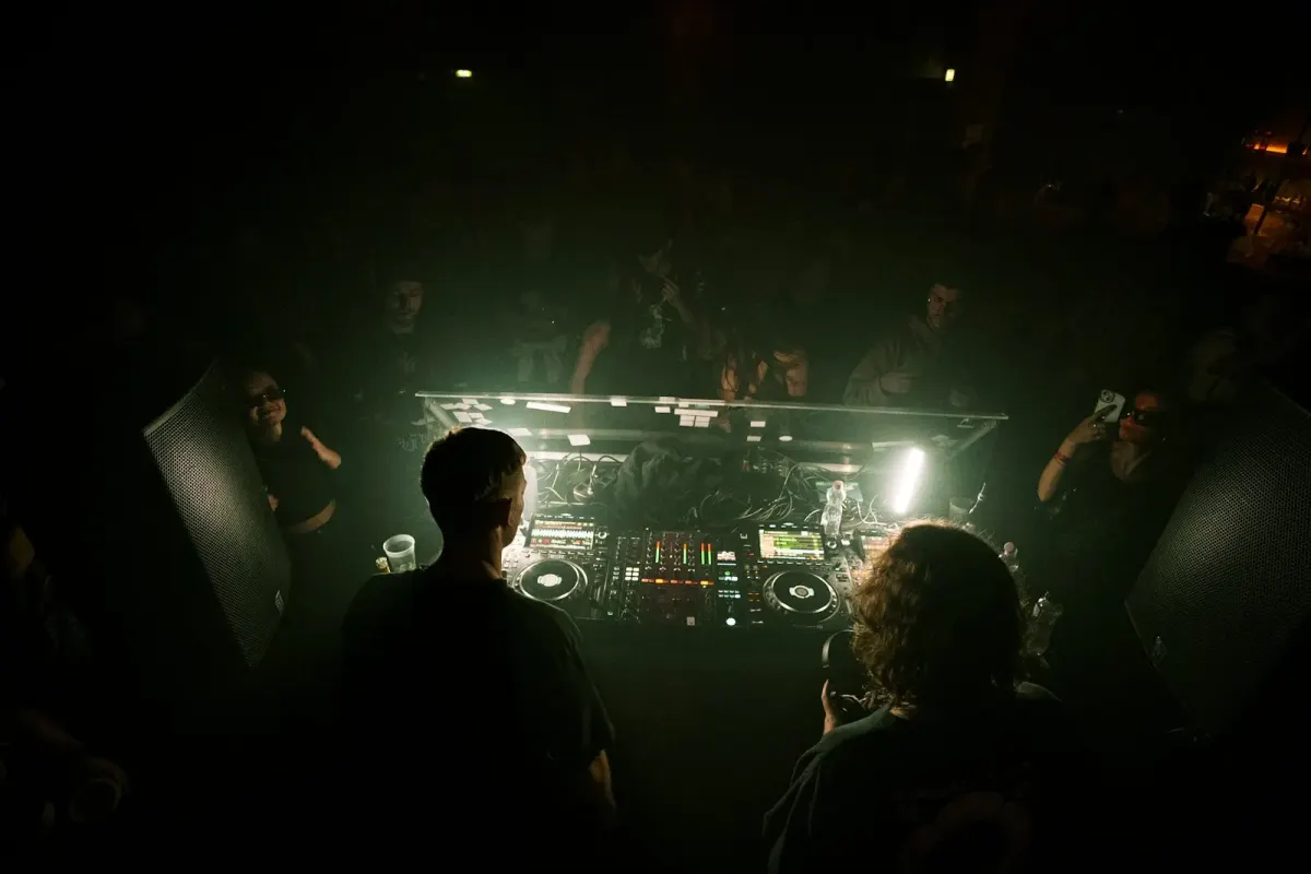DJ booth surrounded by a small crowd at an underground party