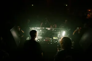 DJ booth surrounded by a small crowd at an underground party
