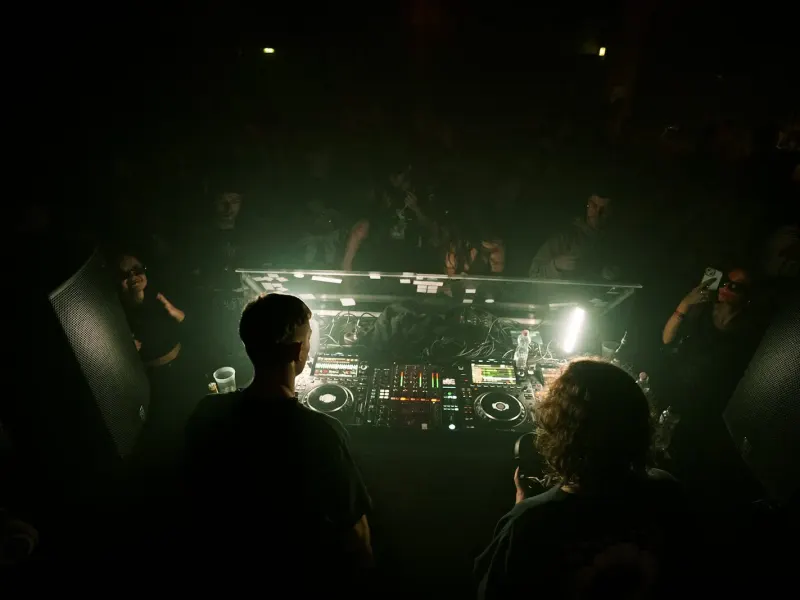 DJ booth surrounded by a small crowd at an underground party
