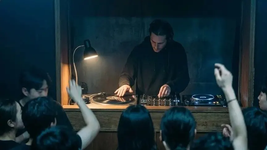 CDJ screen showing waveform with DJ hands in motion