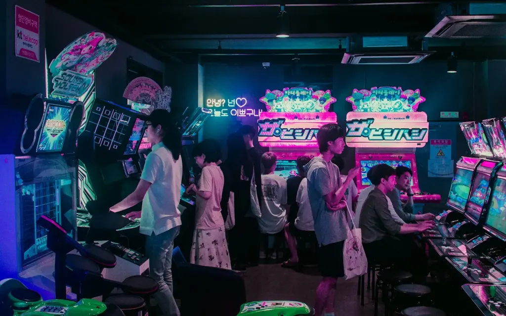 Young people playing games in a neon-lit Korean arcade