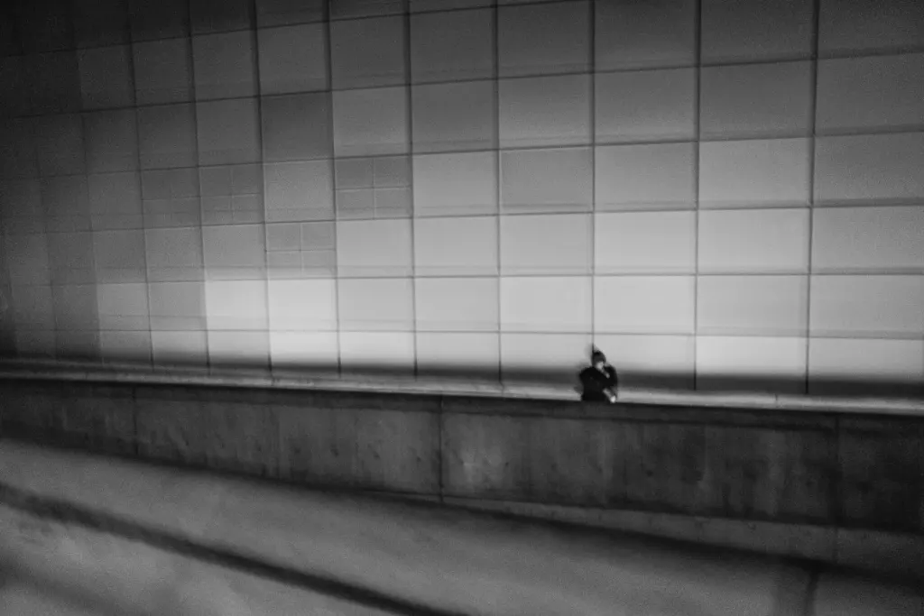 A lone figure against a tiled wall in an underpass