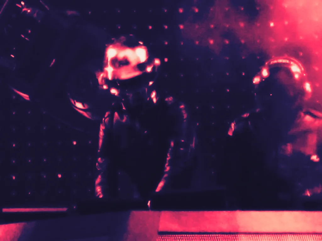 Daft Punk performing in their helmets inside the lit pyramid stage at Coachella in 2006.