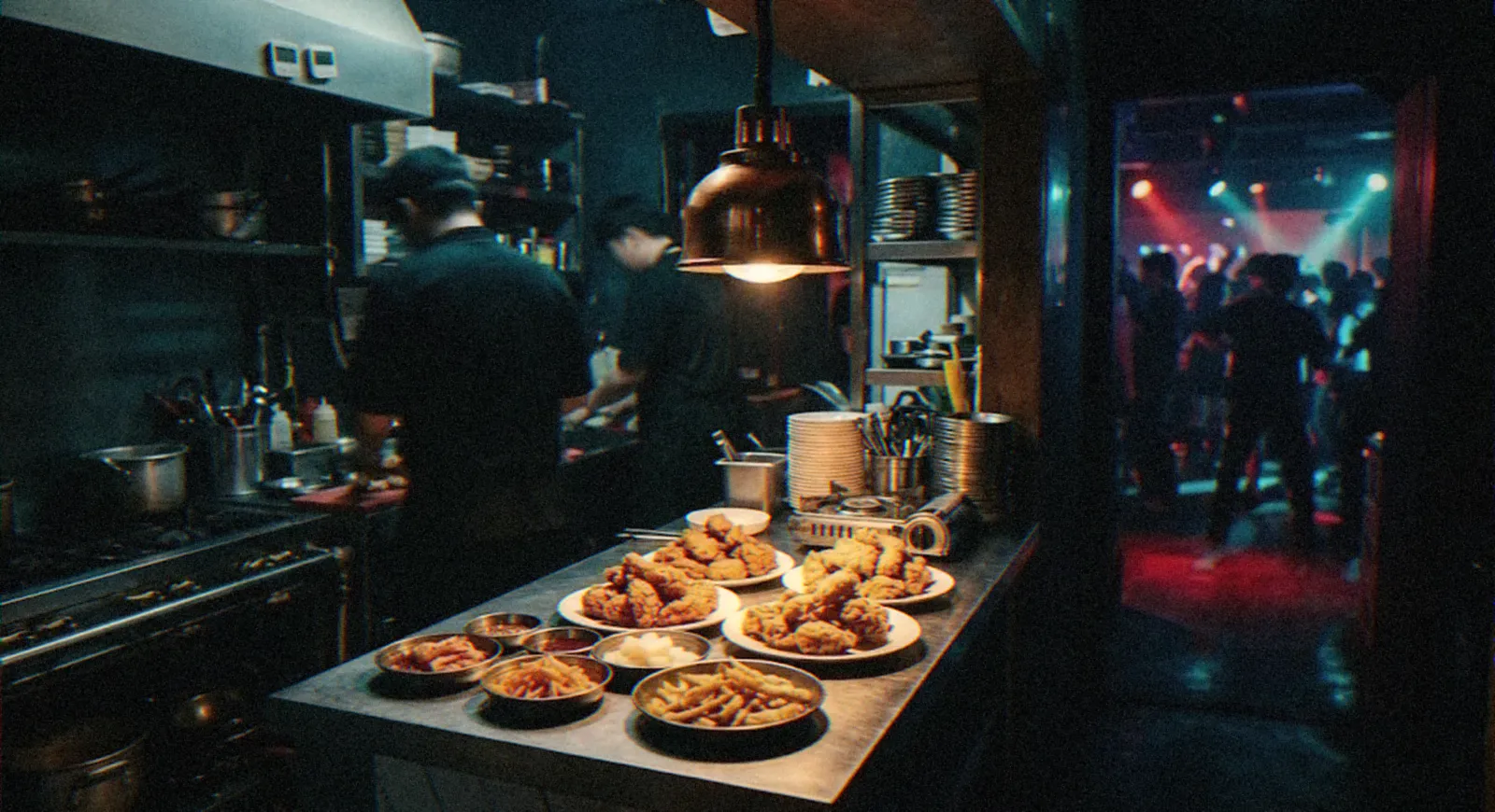 Open kitchen counter with plates of fried food beside a club dancefloor