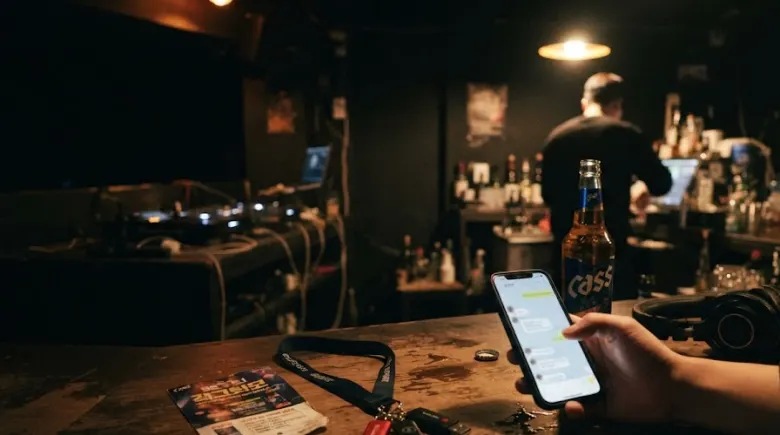 Checking booking messages on a phone at the bar of a Seoul club before opening