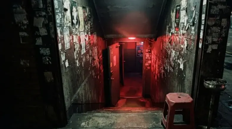Red light spilling up a concrete stairwell into a basement club in Itaewon