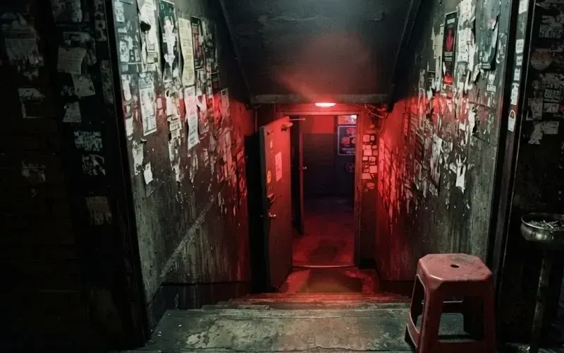 Red light spilling up a concrete stairwell into a basement club in Itaewon