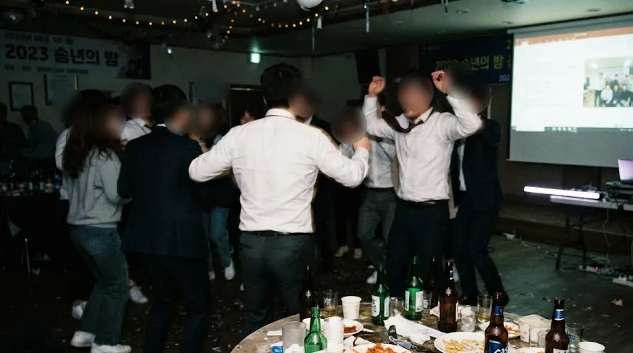 Office workers dancing at a Korean company year-end party, faces blurred