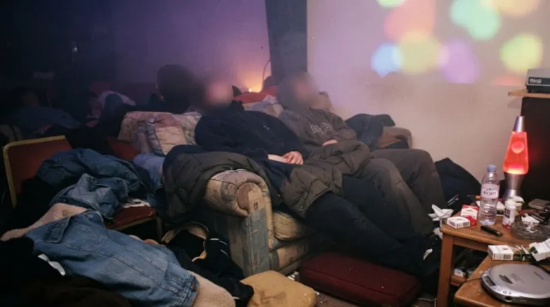 Clubbers slumped on old sofas in a late 1990s chill-out room with a lava lamp