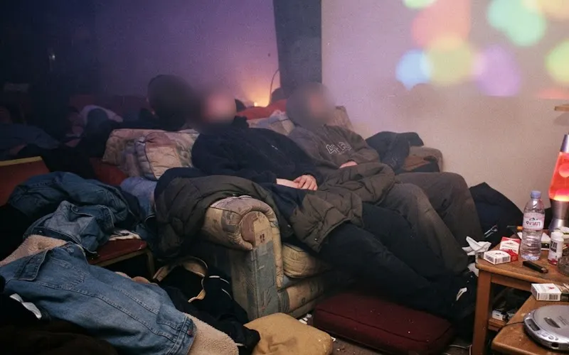 Clubbers slumped on old sofas in a late 1990s chill-out room with a lava lamp