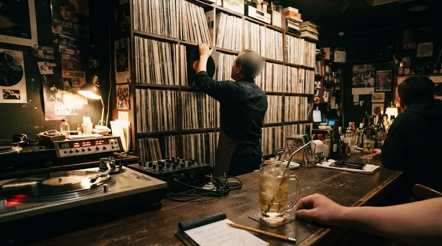 An LP bar owner pulling a record from a wall of vinyl in a narrow Seoul LP bar at midnight