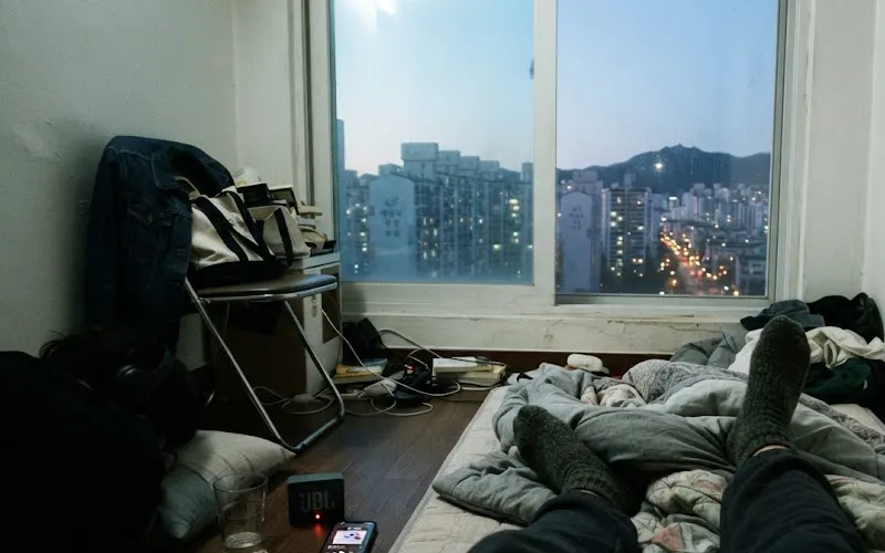 Lying on a floor mattress listening to music as dawn breaks over Seoul apartment blocks
