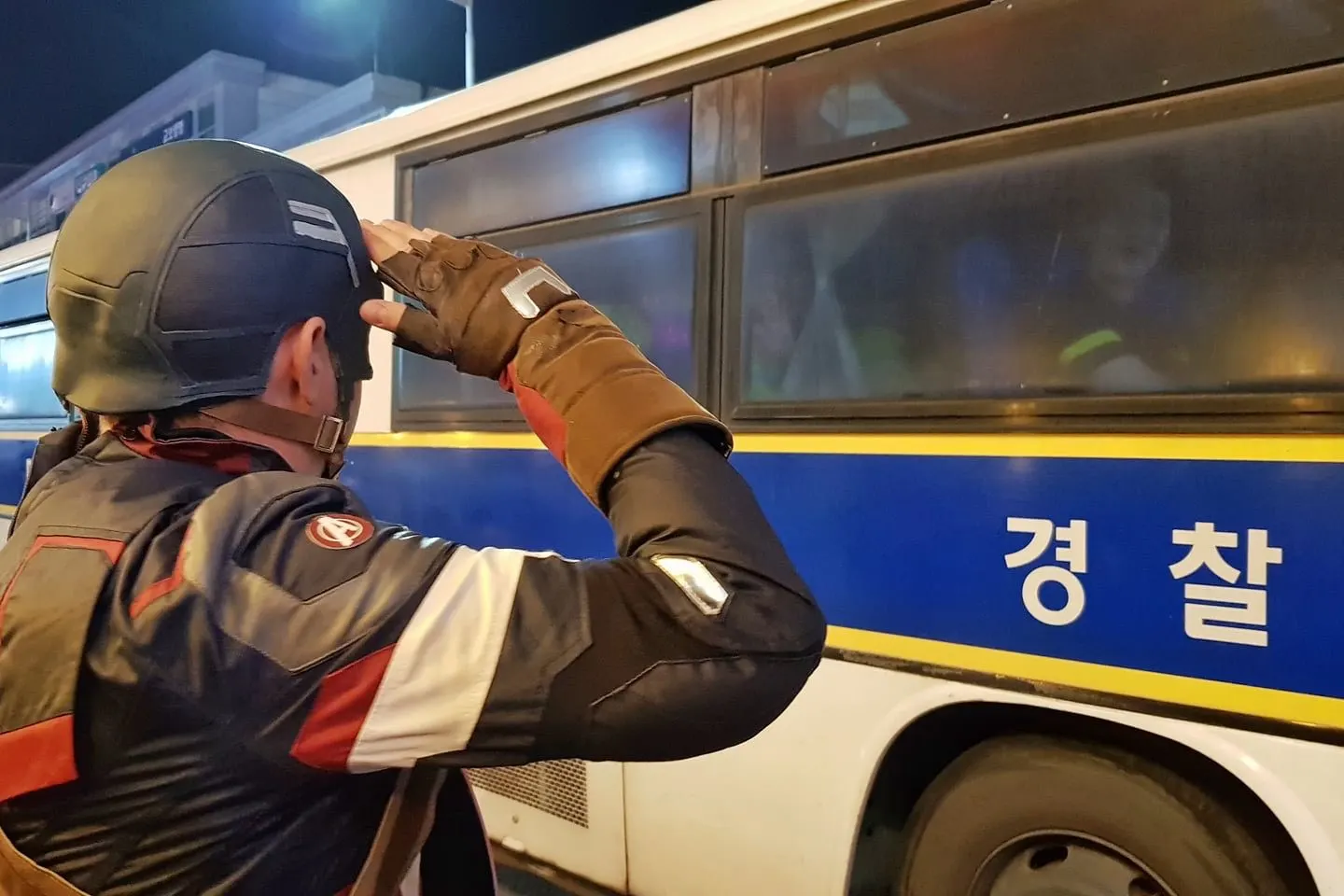 A man dressed as Captain America salutes a police bus on Halloween night