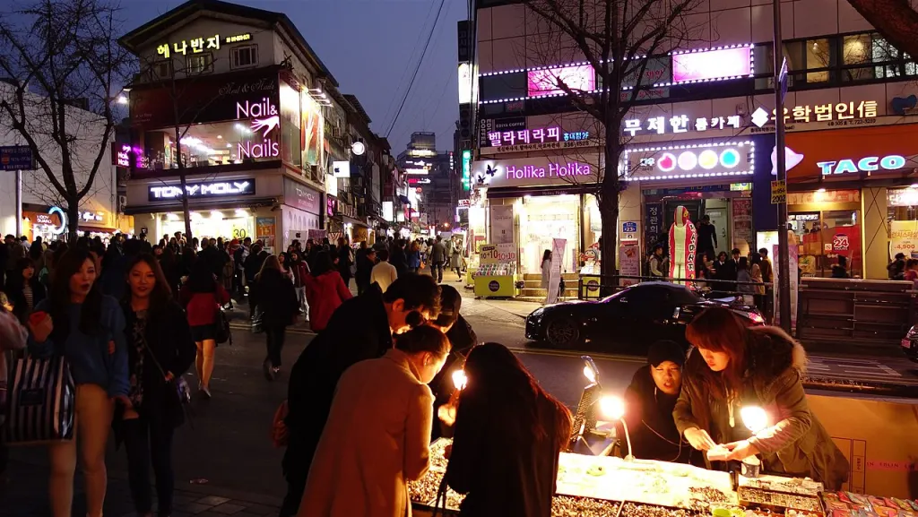 A busy Hongdae street at night with neon signs