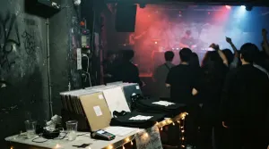 A record label merch table beside the dance floor at a label night in a Seoul basement club